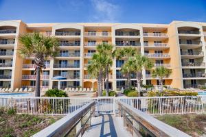 ein großes gelbes Gebäude mit Palmen davor in der Unterkunft Azure 305 - Beachfront Luxury Retreat in Fort Walton Beach