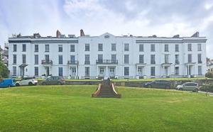 Un gran edificio blanco con coches aparcados delante. en North Devon Luxe Gem for 4, 2 Ensuite Beds, Elegantly Renovated Sea Nearby, en Ilfracombe