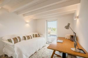 a bedroom with a bed and a desk and a window at Comporta Sunset Villa in Comporta