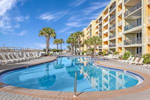 einen Pool vor einem Hotel mit Stühlen und Palmen in der Unterkunft Azure 501 - Beachfront Luxury & Stunning Ocean Views! in Fort Walton Beach