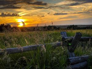 a wooden fence in a field with the sunset in the background at Golden Eagle Getaway w/Hot Tub! in Gallatin Gateway