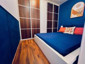 a small room with a bed with blue walls at Doux Pavillon - Le Strada - box - air conditioning - tram 5 min away in Villeurbanne
