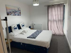 a bedroom with a large bed with white sheets and blue pillows at Heathrow central suites in Colnbrook