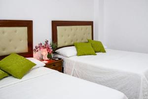 two beds with green pillows in a bedroom at Posada Sueño Real in San Martín