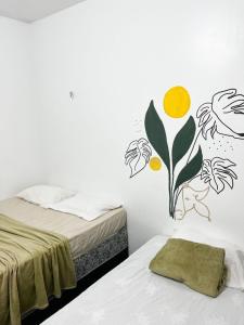a bedroom with two beds with a flower mural on the wall at Pousada Marajó For You in Soure