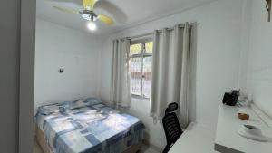 a bedroom with a bed and a desk and a window at Conforto e localização in Vila Velha