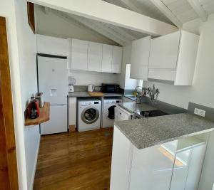 a kitchen with white cabinets and a washer and dryer at Casa do Octavia in Corvo