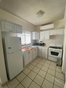 a kitchen with white cabinets and a white refrigerator at Bonita Casa Centrica a 10 min del malecon in La Paz
