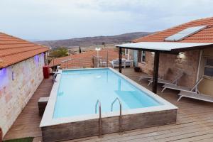 a large swimming pool on a deck next to a house at mimar מימאר אירוח כפרי מפנק in Had Nes