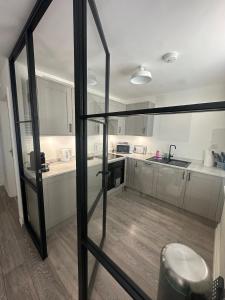 a kitchen with white cabinets and a glass door at House by the Sea, Worthing in Worthing