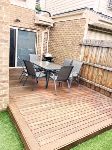 メルボルンにあるLight and Bright 2-bedroom Townhouse with Patioの木製デッキ(テーブル、椅子付)