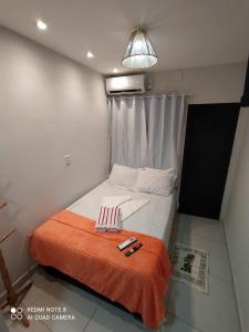 a small bedroom with a bed with an orange blanket at Casa Laranja no Centro de Pipa a 3 min das Praias in Pipa
