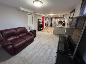 a living room with a brown leather couch and a kitchen at Basement Unit 2br 2ba in Barnum West Near Belmar and Sloan Lake 10 mins to Downtown in Denver