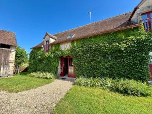 an ivy covered house with a red door at Gîtes avec piscine partagée dans la Brenne, proche sites historiques - FR-1-591-120 in Rosnay