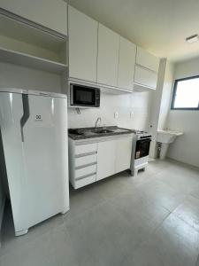 La cuisine blanche est équipée d'un réfrigérateur et d'un évier. dans l'établissement Ap em Juazeiro do Norte com dois quartos com cama de casal e ar condicionado, à Juazeiro do Norte