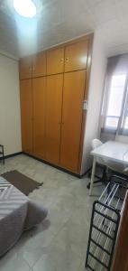 Pokój z dużą drewnianą szafką i stołem w obiekcie Habitación Individual en Vivienda Compartida w Walencji