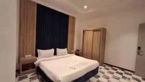 a bedroom with a bed with white sheets and a window at فندق كوثر التميز in Taif