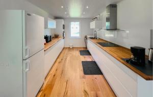 a kitchen with white cabinets and a wooden floor at Gorgeous Home In Väversunda With House Sea View in Väversunda