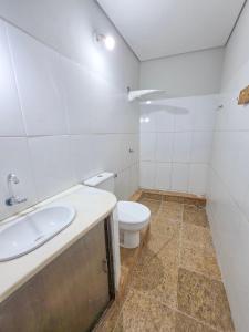 a white bathroom with a toilet and a sink at Hospedaria 33 in Barretos