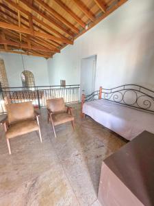 a bedroom with a bed and two chairs at Hospedaria 33 in Barretos