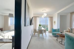 a bedroom and living room with a bed and a table at Beachside 1BDR Dreamy Apt.| BBQ + Pool & Sea View in Juan Dolio +74 photos