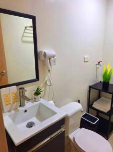 a bathroom with a sink and a toilet and a mirror at Hill Residences by KJA in Manila