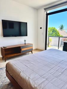 a bedroom with a large bed and a flat screen tv at Bright Ocean View Studio with Rooftop Pool Access in Puerto Morelos +16 photos