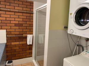 a bathroom with a shower and a washing machine at Northpoint Holiday Apartments in Alexandra Headland +92 photos