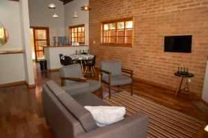 a living room with a couch and a brick wall at Villa da Serra - Casa 02 in São Bento do Sapucaí