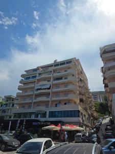 a large building with cars parked in a parking lot at Elena Seaview Apartment in Vlorë