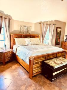 a bedroom with a large wooden bed and windows at Birders' Paradise With Private Pool & Epic Views in Santa Elena