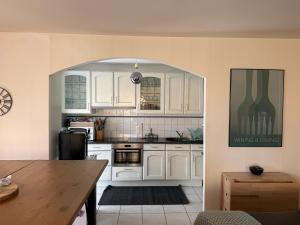 a kitchen with white cabinets and a wooden table at Aux portes de Genève - Chambre Individuelle in Saint-Julien-en-Genevois