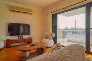Una sala de estar con un sofá y una mesa y una ventana grande. en Adorable Apartment with stunning Nile view, en El Cairo