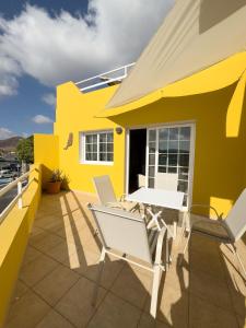 a yellow house with chairs and a table on a balcony at Stellina Mar 1 in Tarajalejo