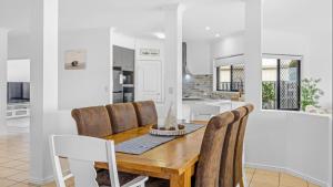 a kitchen and dining room with a wooden table and chairs at Tranquil Canal Front Holiday House in Banksia Beach
