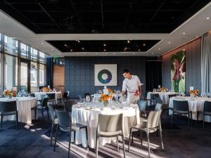 a man standing in a dining room with tables at The Loren Hotel Austin in Austin