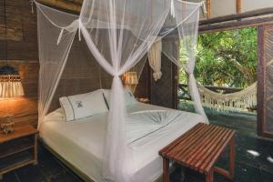 a bedroom with a bed with mosquito net at Hotel Isla Fuerte Ecohouse in Puerto Limón