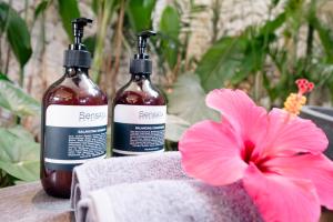 zwei Flaschen Seife und eine rosa Blume auf einem Tisch in der Unterkunft Luxury 2-Bedroom Villa with Private Pool - Uluwatu in Ungasan + 25 Fotos