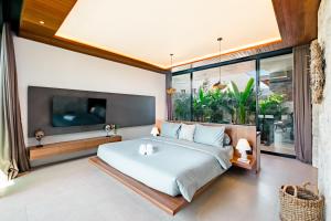 ein Schlafzimmer mit einem großen Bett und einem Fernseher in der Unterkunft Luxury 2-Bedroom Villa with Private Pool - Uluwatu in Ungasan