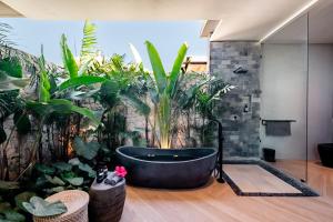 ein Badezimmer mit schwarzer Badewanne und Pflanzen in der Unterkunft Luxury 2-Bedroom Villa with Private Pool - Uluwatu in Ungasan