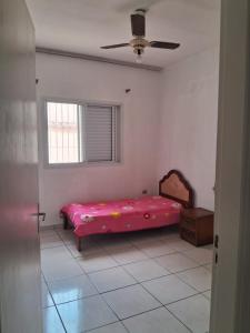 a bedroom with a pink bed and a window at Tati casa in Peruíbe