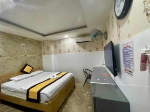 a bedroom with a bed and a desk with a tv at HOTEL Ánh Hồng in Ho Chi Minh City