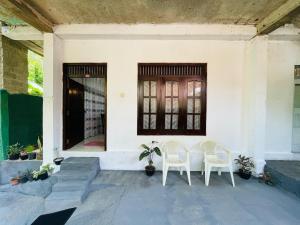 two white chairs sitting on the porch of a house at Kenashi Green Villa in Weligama