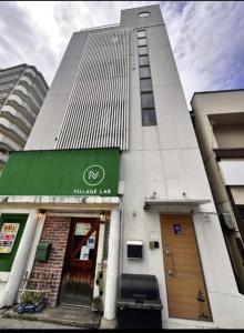 un edificio alto con una tenda verde sopra di R Inn岸里 R-Inn Kishinosato ad Osaka