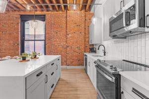 Una cocina con encimeras blancas y una pared de ladrillo. en Express Yourself! Stay in This Stylish Guest Fave!, en Saint Louis