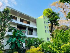 a green building with trees in front of it at Olas de Oro in Nicoya