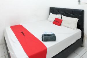 a bed with a red and white blanket and a purse at RedDoorz near Bigmall Samarinda 2 in Samarinda