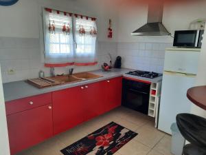 a kitchen with red cabinets and a sink and a stove at Villa Les Flambloyants in Baréto +3 photos