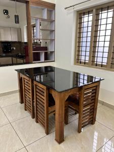 a dining table with a glass top in a kitchen at Ayat Apartments - near to Rajagiri Hospital in Alwaye +13 photos
