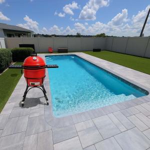 a barbecue grill sitting next to a swimming pool at Luxury Groveland Villa with Pool, Grill & Office in Groveland